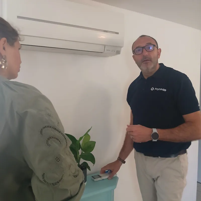 Guillaume Pons et une propriétaire devant l’unité intérieure d’une climatisation