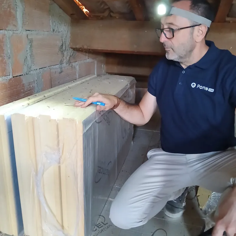 Guillaume Pons désigne des panneaux d’isolant dans des combles