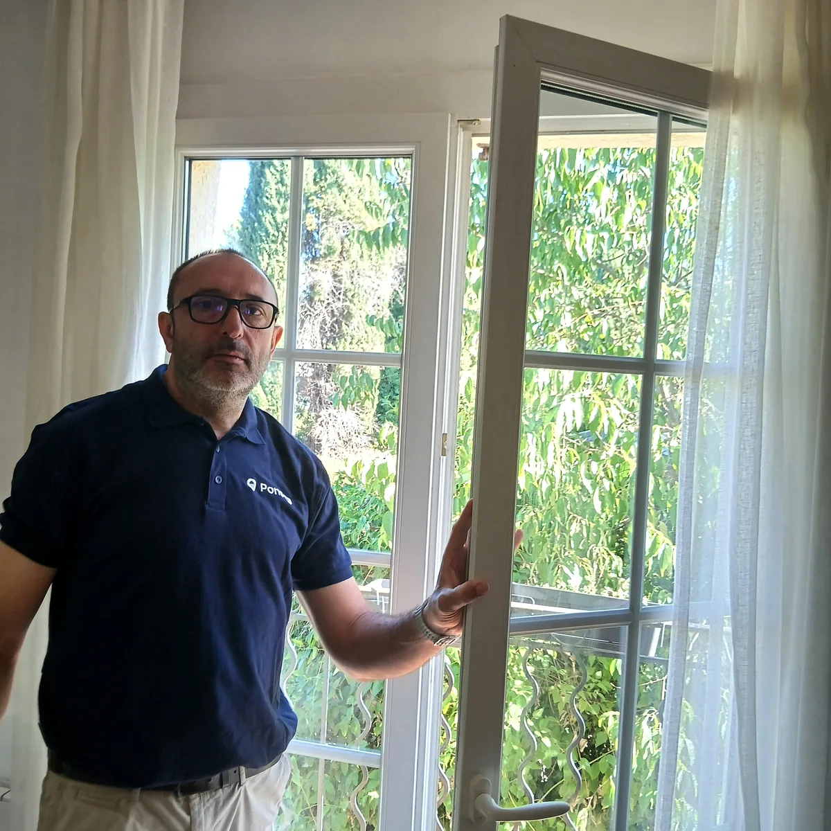 Guillaume Pons, la main sur le montant d’une fenêtre, dans une pièce lumineuse