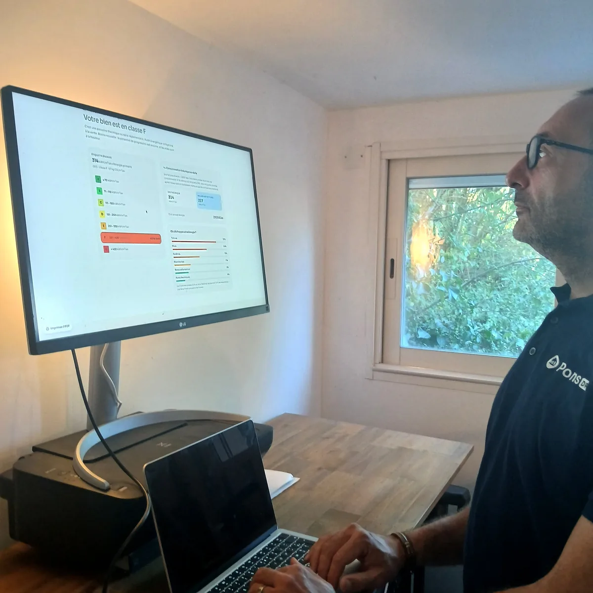 Guillaume Pons devant l’échelle des classes énergétiques du rapport interactif, sur grand écran