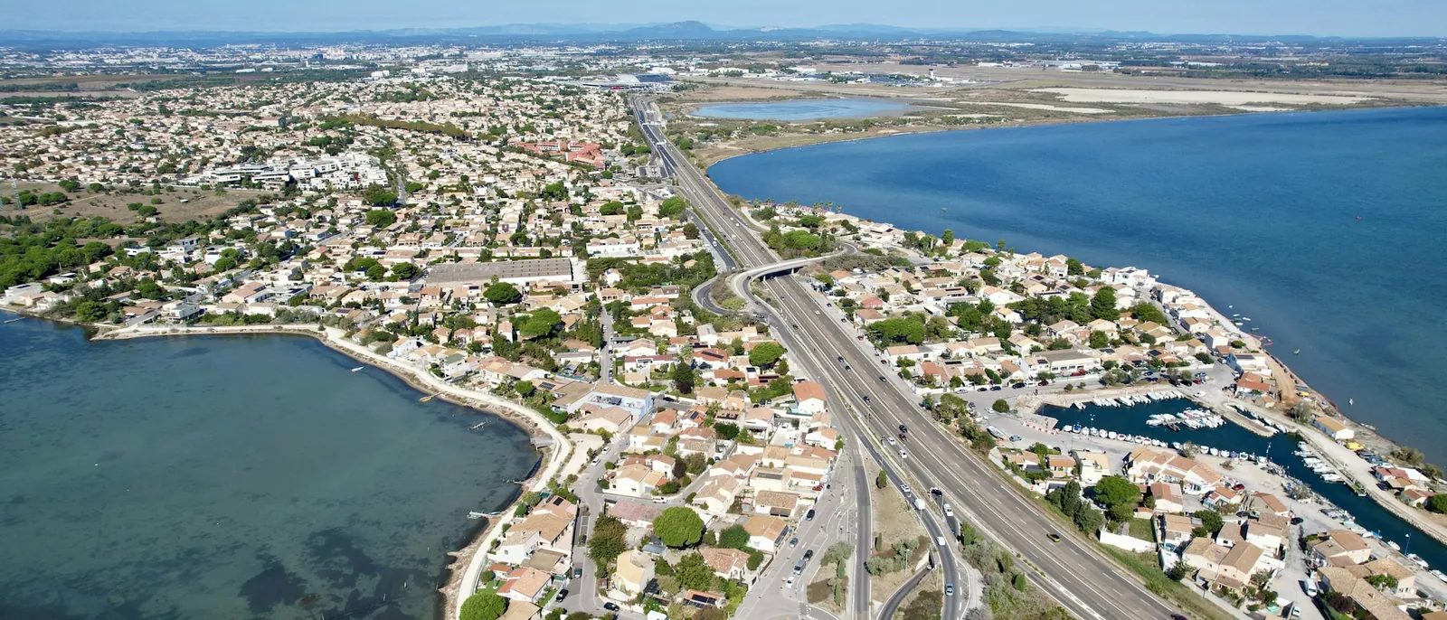 Vue aérienne du littoral montpelliérain : lotissements, étang et voie rapide vers la mer